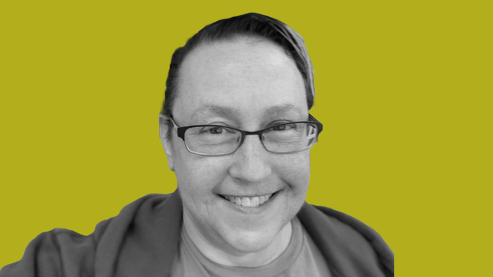 Tracy Fullerton in black and white, smiling at the camera, in front of a grokludo yellow background.