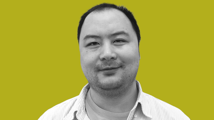 Wen You Ge AKA "Bearlike" in black and white, smiling at the camera, in front of grokludo yellow.